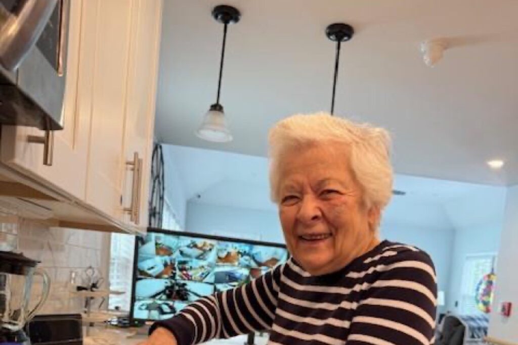 Smiling resident standing in the bright, sunlit kitchen of the care home