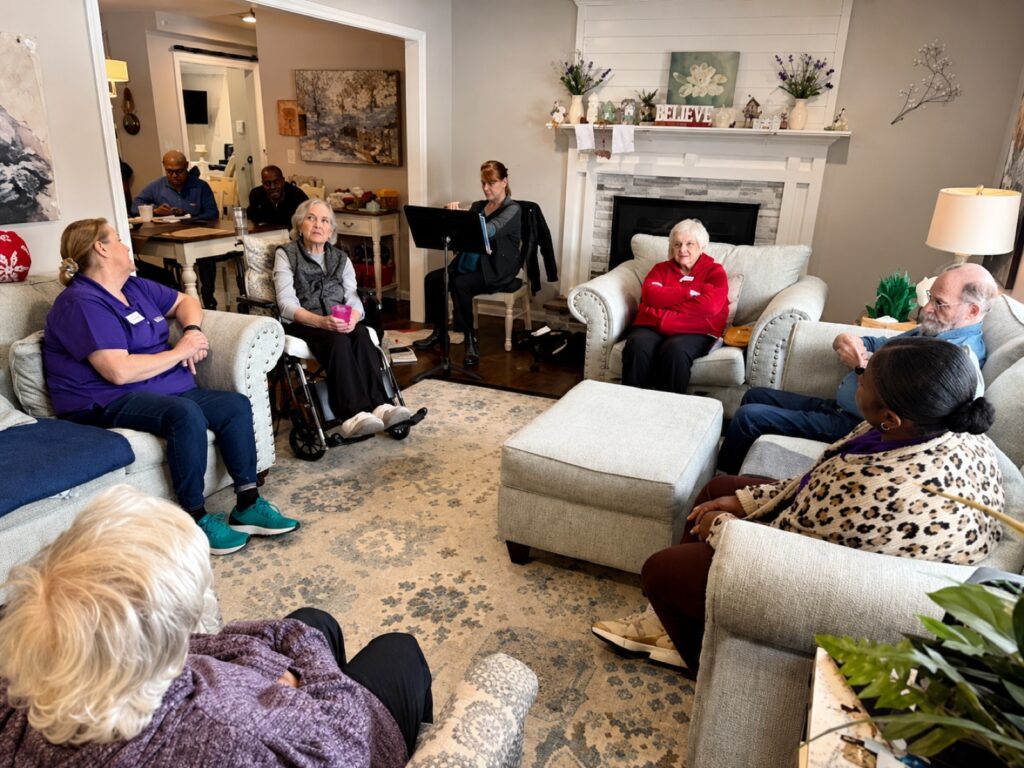 Residents and caregivers gathered in the living room around the fireplace for a group activity
